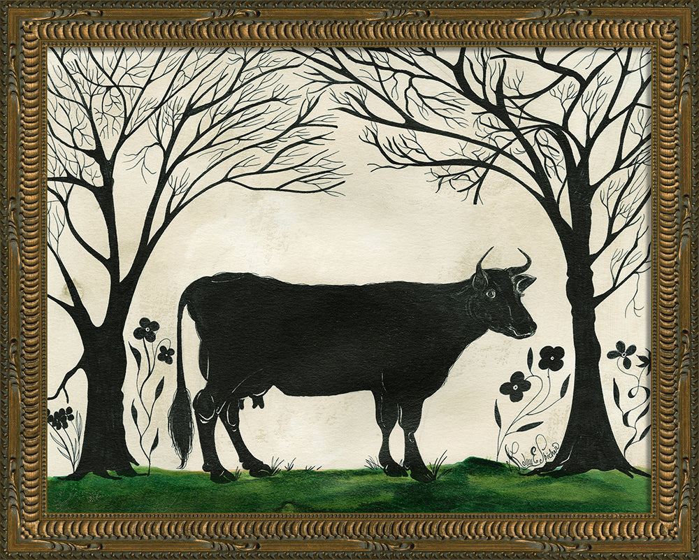 A piece of artwork featuring a silhouette of a cow standing in a field with trees and flowers in the background, framed in a decorative gold frame.